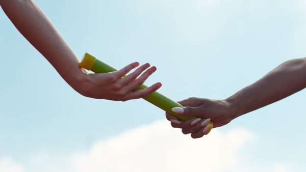 Image of relay runners exchanging a baton to illustrate handover story